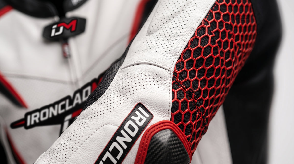 Close-up of a white leather motorcycle jacket with red honeycomb protective panels and black accents, featuring the Ironclad and iM logos.